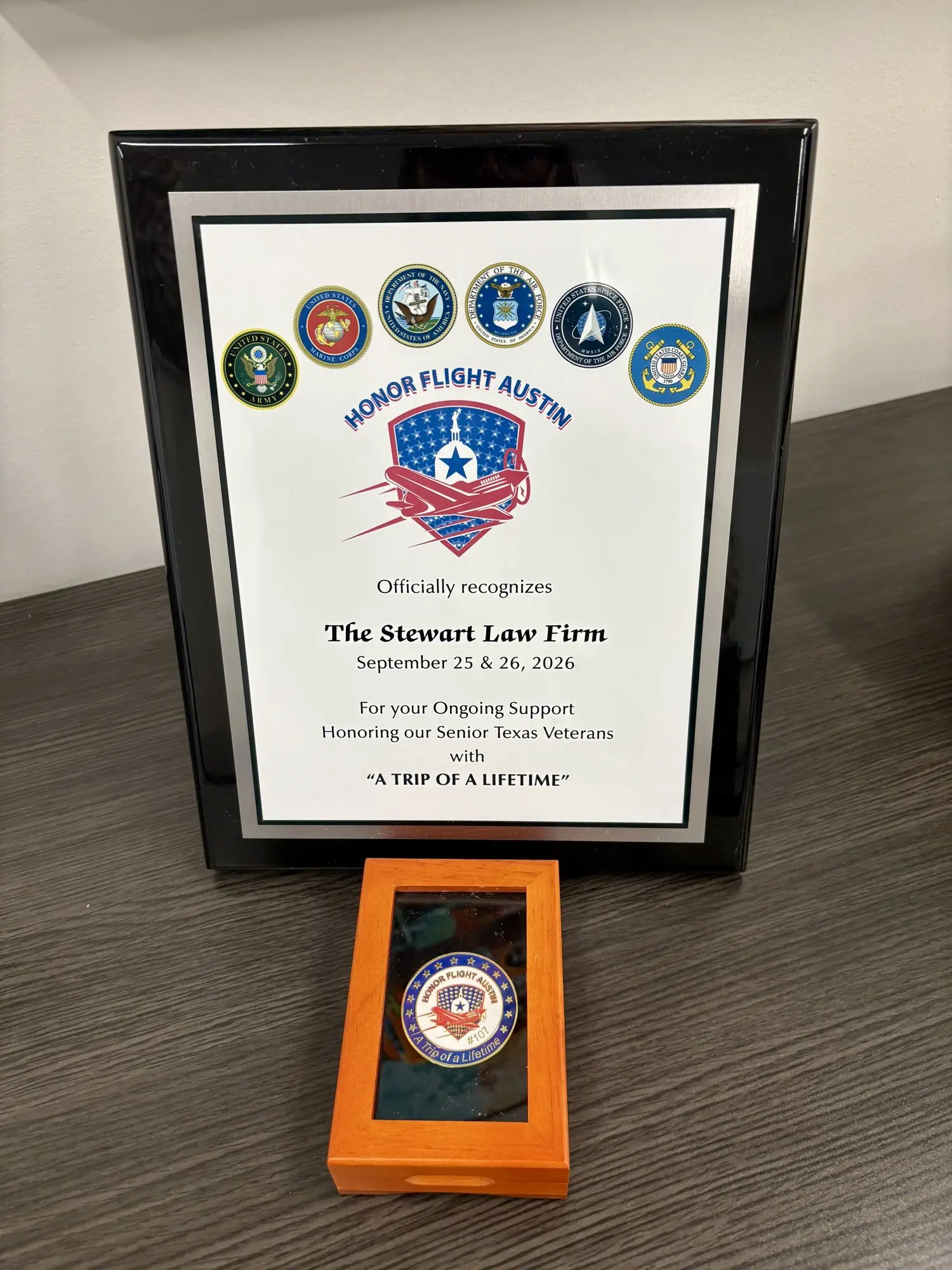 Honor Flight Austin plaque recognizing The Stewart Law Firm for Flight 107, September 25–26, 2026, with challenge coin