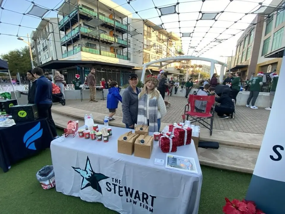 Ginger Stewart and Jordan at The Stewart Law Firm booth at the 2025 Austin Jingle Bell 5K