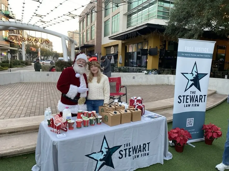 Santa and Jordan at The Stewart Law Firm booth at the 2025 Austin Jingle Bell 5K
